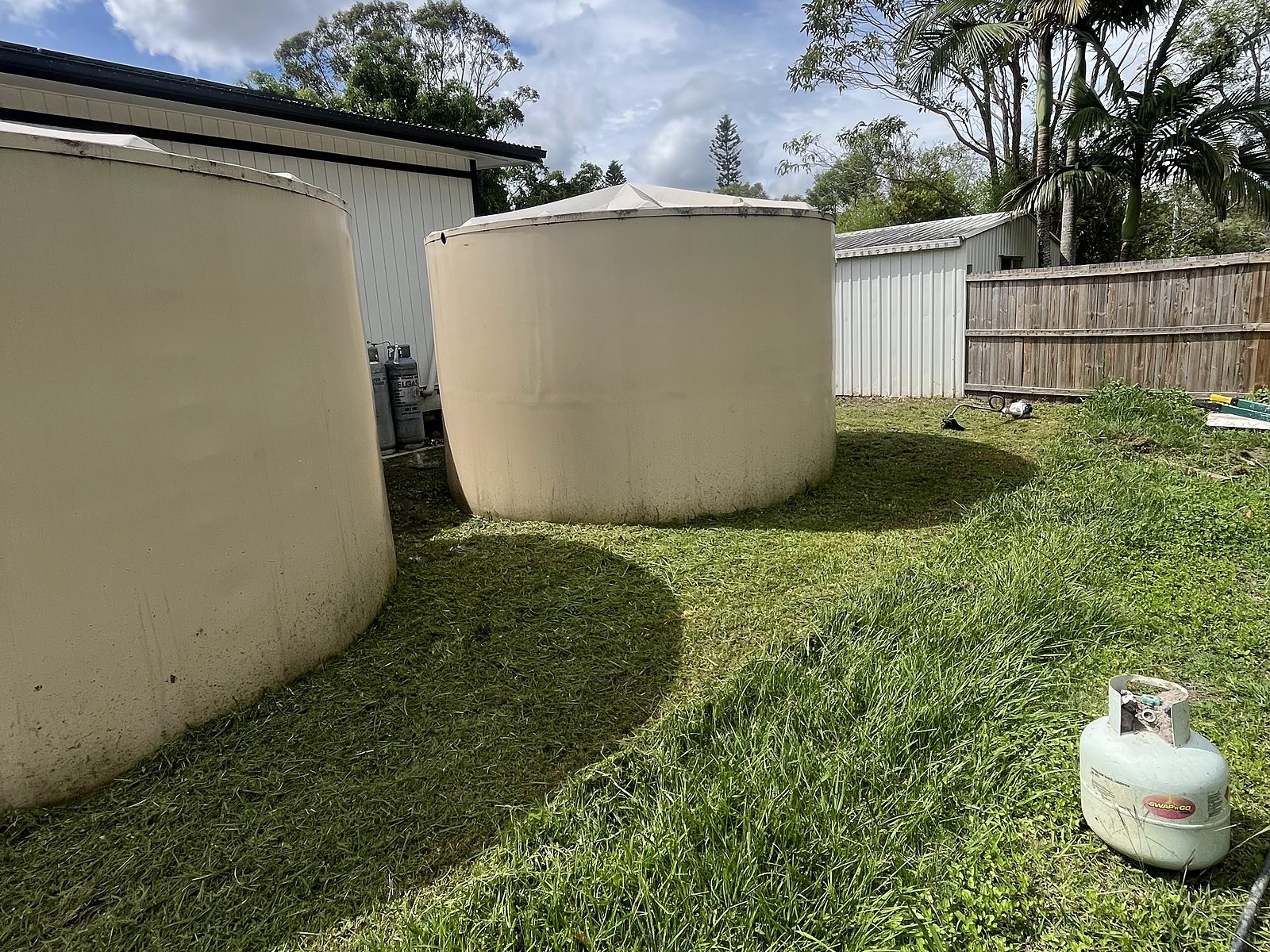 Water tanks sitting on long grass before the job